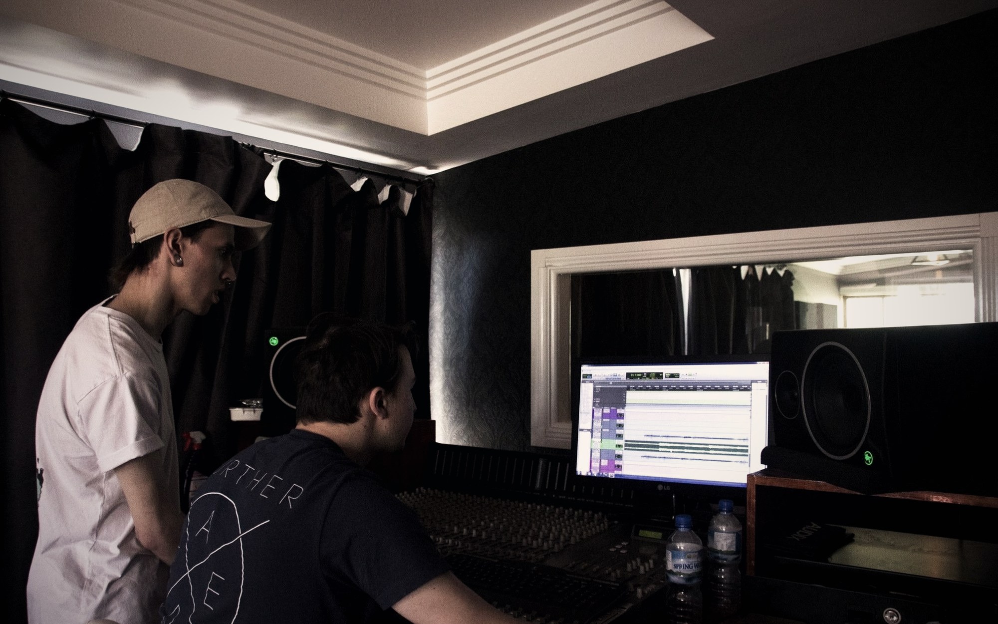 Two people at a studio console with a session open on screen
